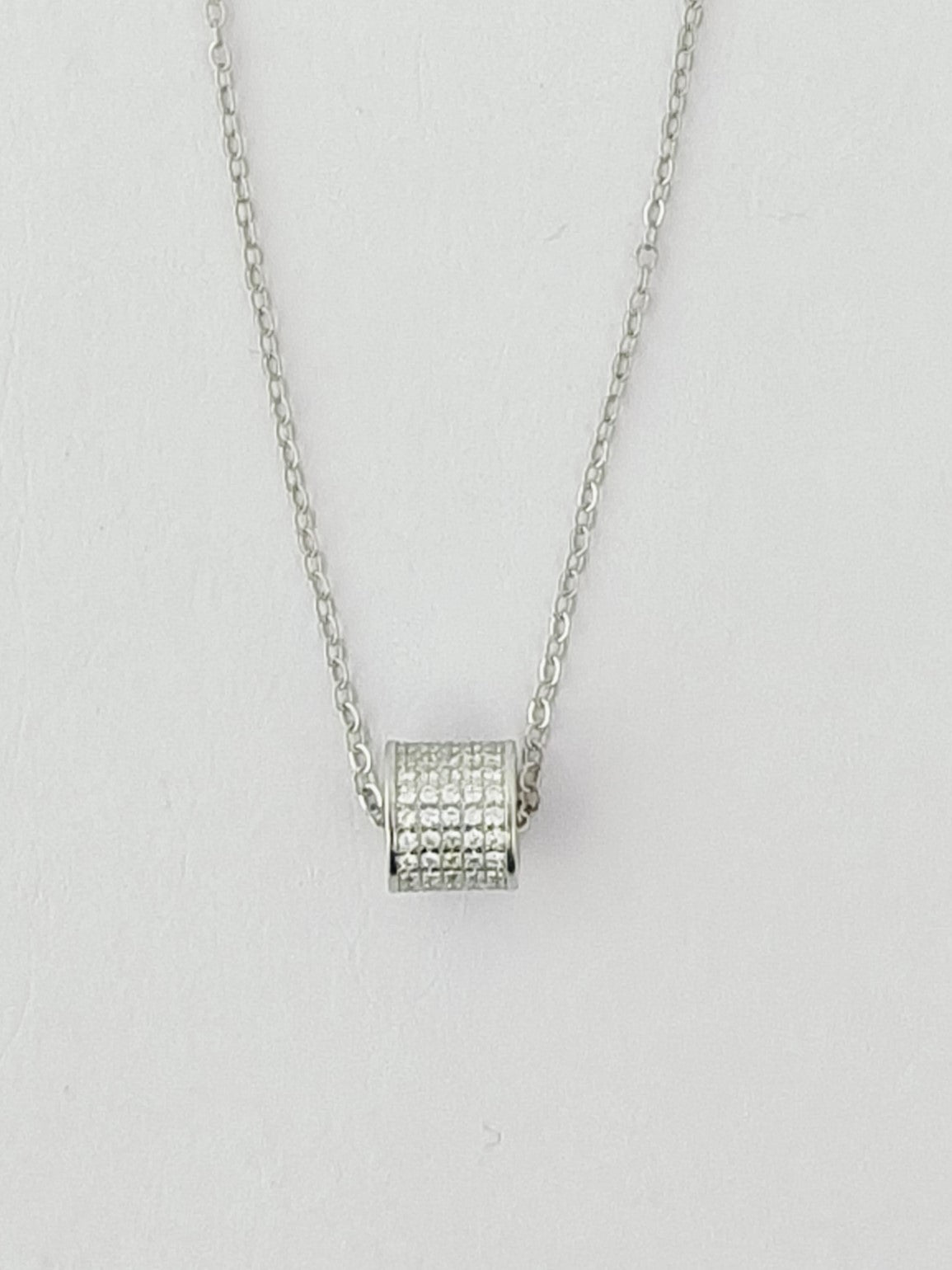 Silver necklace with a square pendant on a light gray background